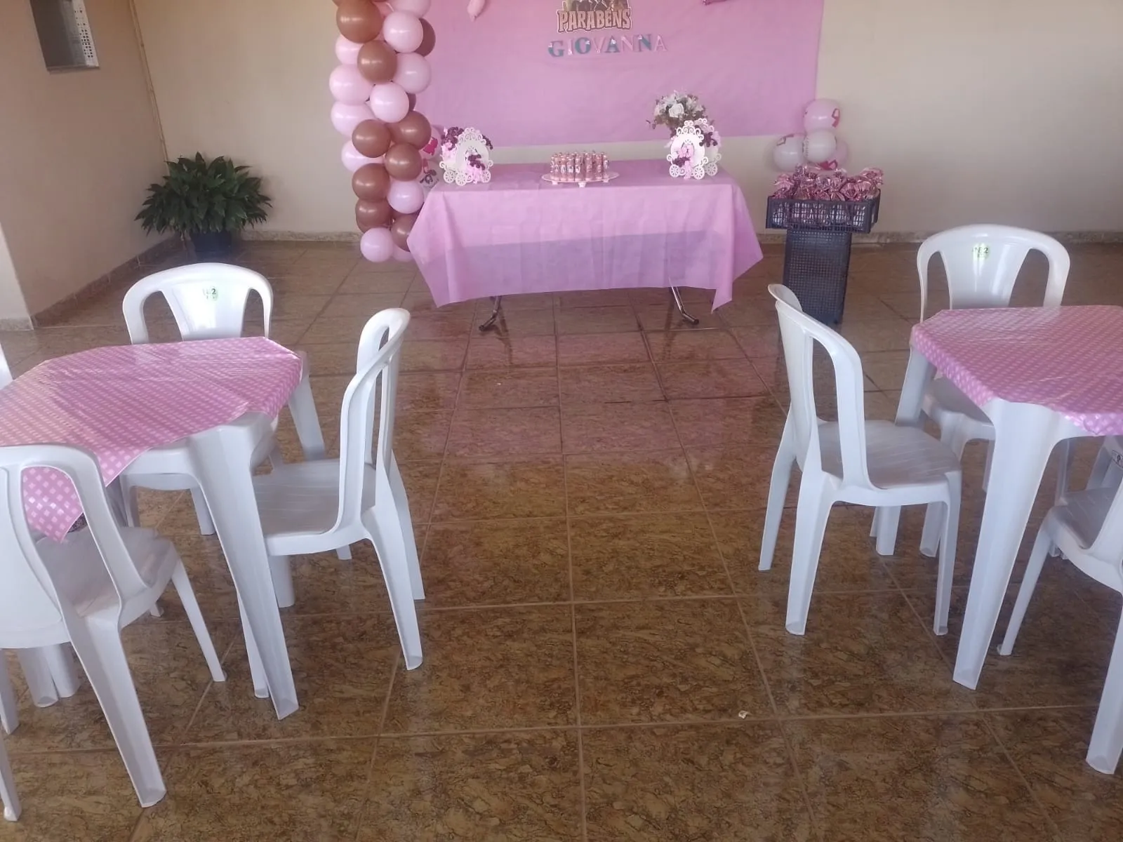 Aniversário infantil com mesas de toalha rosa e mesa do bolo decorada