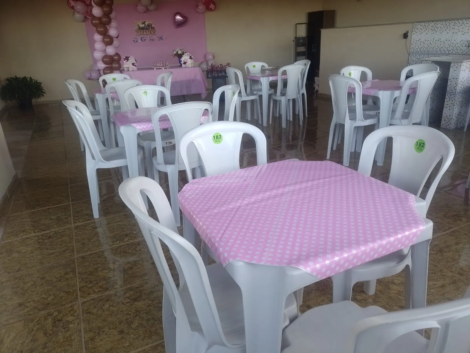 Salão de festa infantil com mesas cobertas por toalhas rosa e cadeiras brancas da Giro Festas